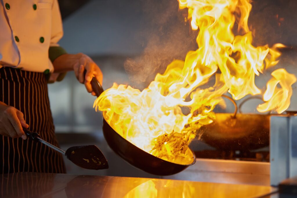 A chef cooking something in a flaming pan, chefs hold the key to building and expanding food culture