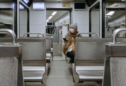 Woman sitting on empty train wearing a facemask looking at phone. A photo taken during the covid 19 pandemic